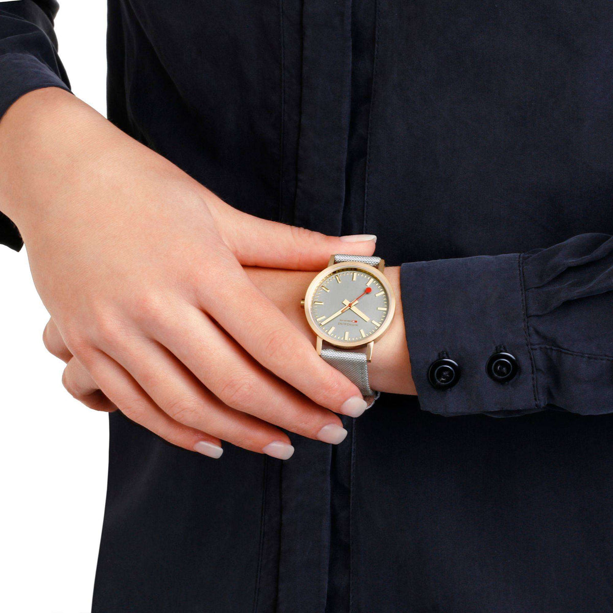 Mondaine quartz watch on wrist with gold case and light beige textile strap