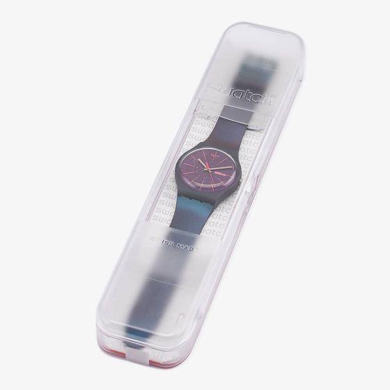 Watch in clear box with purple dial, silver hands, and steel mesh Milanese strap.