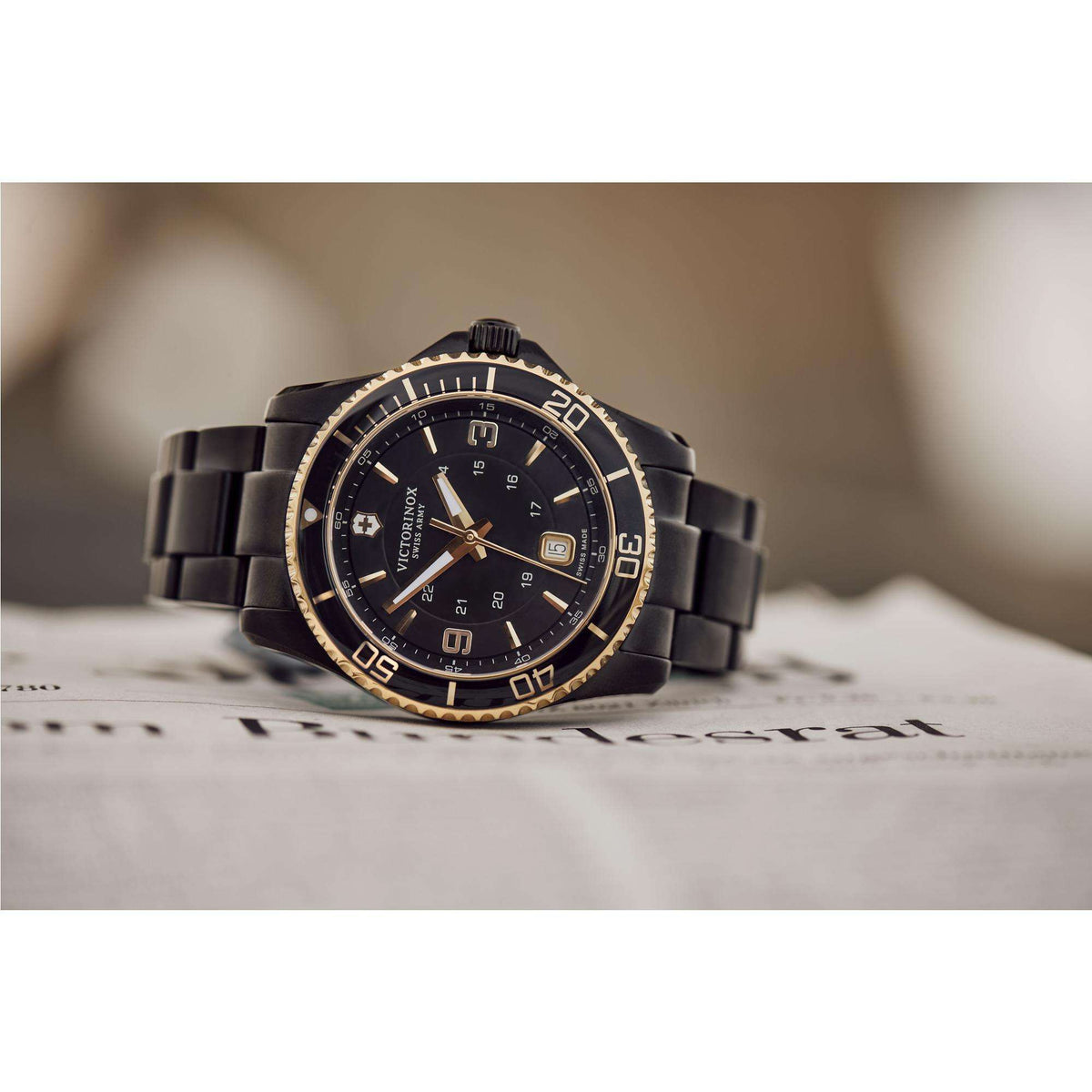 Men's black steel quartz wristwatch with black dial and gold bezel, resting on a card