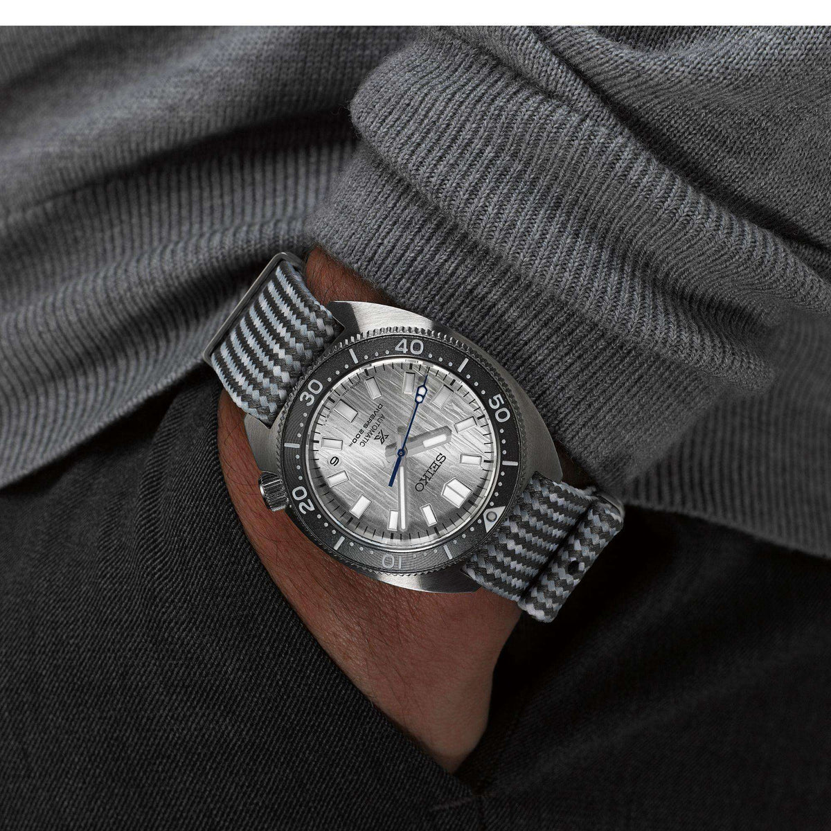 Seiko Prospex SPB333J1 watch with a textured strap worn on a wrist against a gray sweater background
