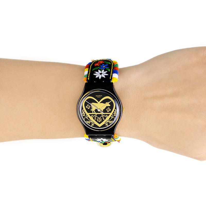 Black ladies wristwatch on wrist with gold heart dial and colorful embroidered strap