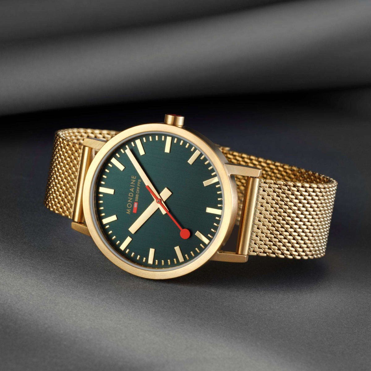 Gold mesh bracelet analog watch with dark green dial, red seconds hand, and gold indices