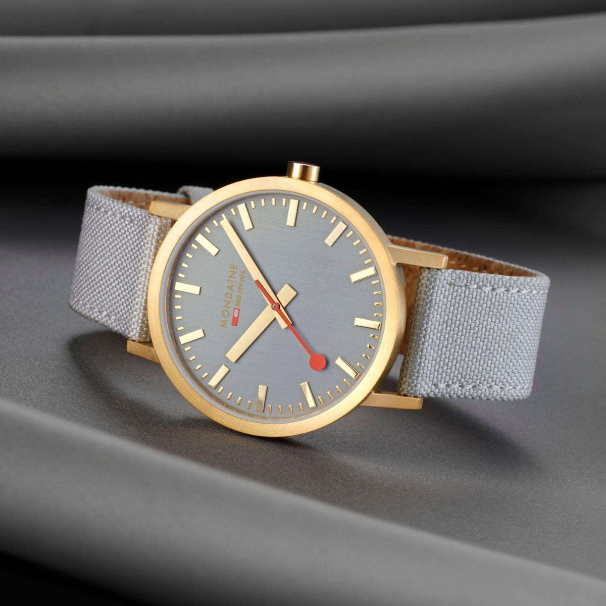 Mondaine classic 40mm quartz watch close-up, grey dial and gold-tone case with grey strap