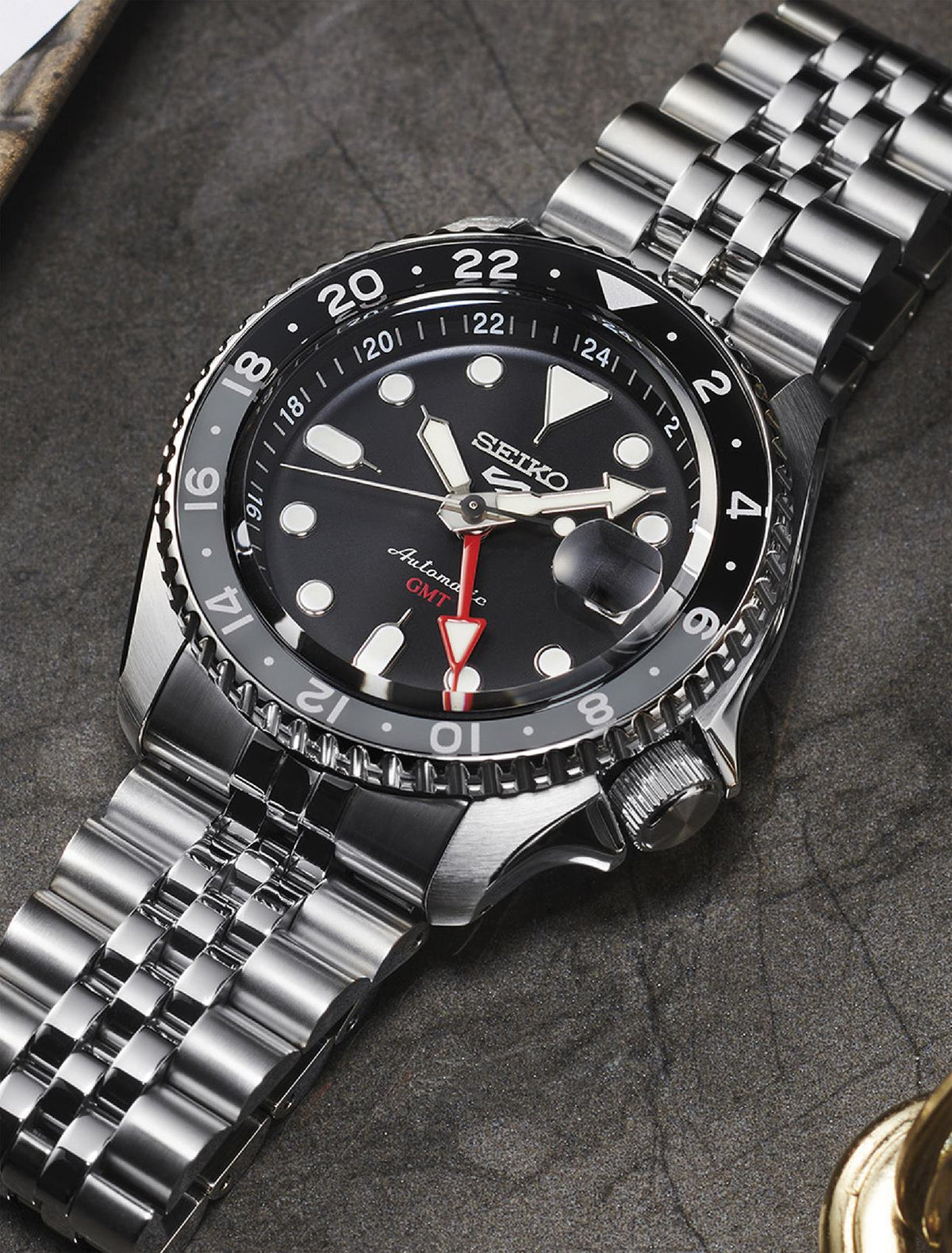 Men's black dial GMT watch, steel bezel and bracelet, date window and red GMT hand visible