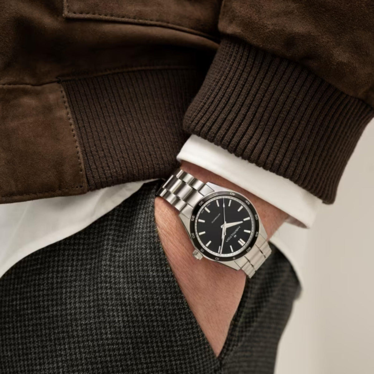 Men's automatic wristwatch with black dial on wrist, steel bracelet and silver bezel.