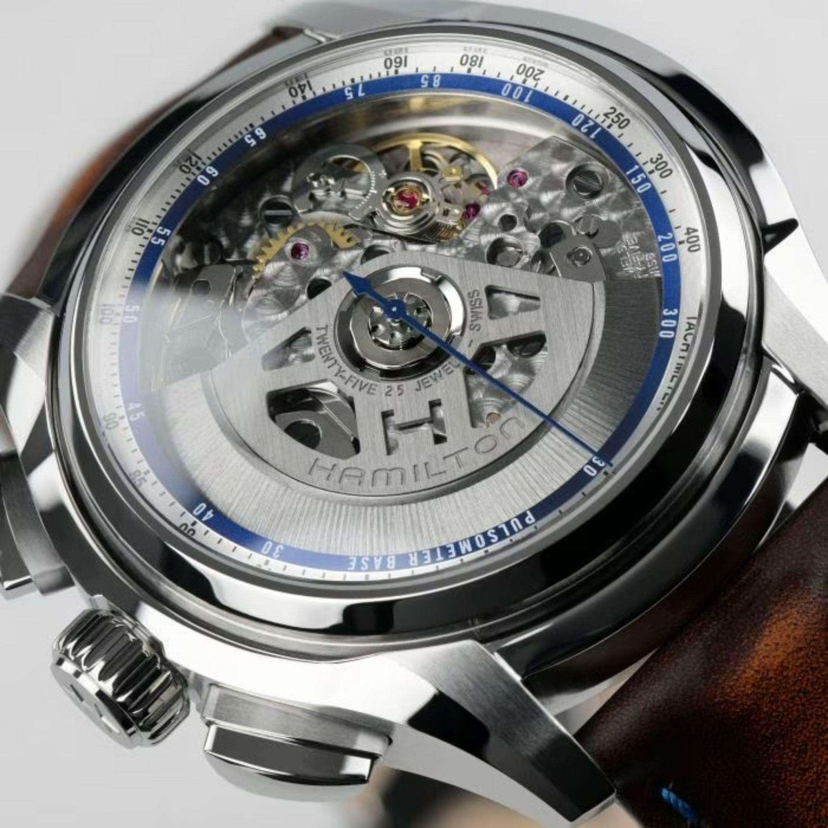 Men's silver automatic watch open caseback with visible movement and brown leather strap
