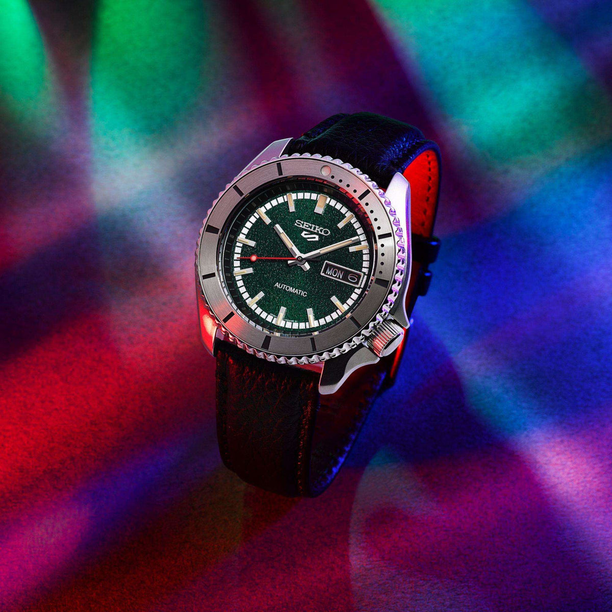 Seiko 5 Sports x Masked Rider 43mm watch displayed against a dramatic red, green, and blue lighting background.