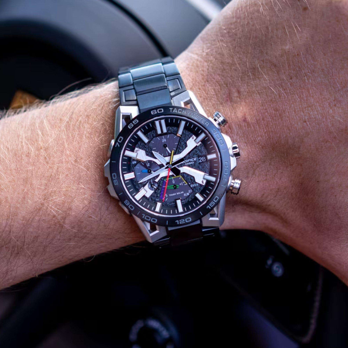Men's solar chronograph watch on wrist, dark grey dial, black metal bracelet, silver case