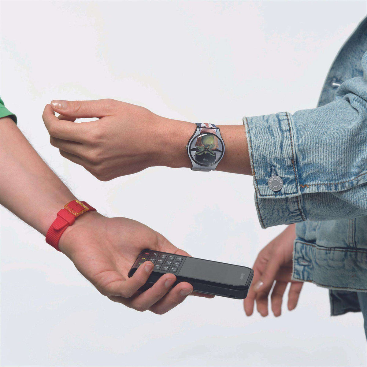 Graphic-dial watch on wrist with gray silicone strap, worn with denim jacket