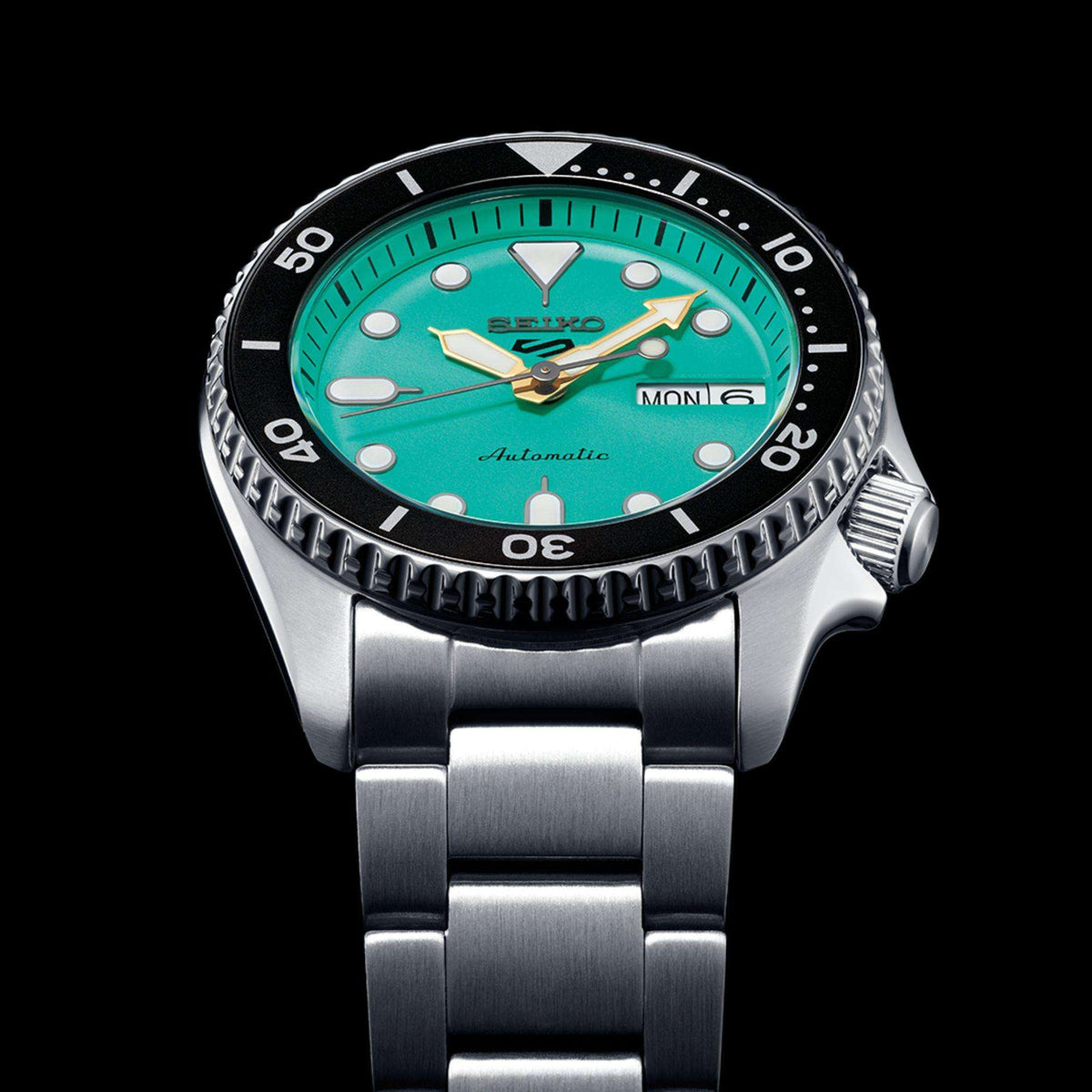 Low-angle view of Seiko 5 Sports Teal Dial Mens Watch against a solid black background, emphasizing the brush-finished steel bracelet links.