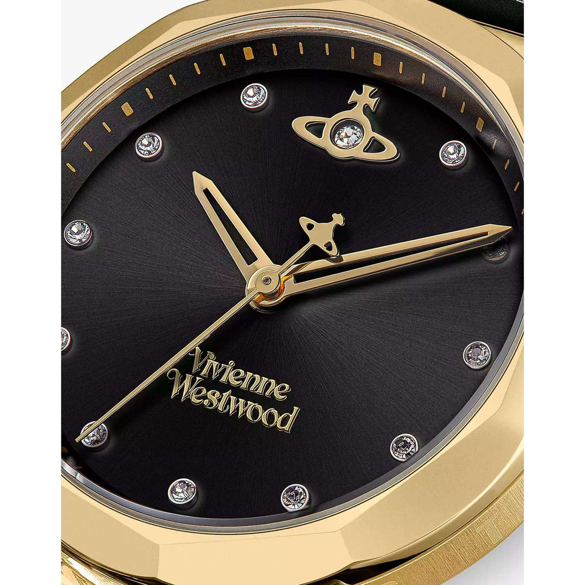 Close-up of black watch dial with gold hands, logo hour markers, and crystal details