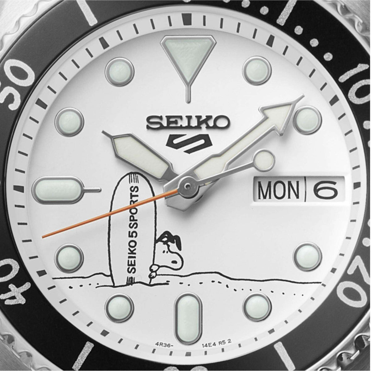 Close-up of the white dial of the Seiko 5 Sports X Peanuts Surfboard watch SRPK25K1 showing Snoopy next to a surfboard.