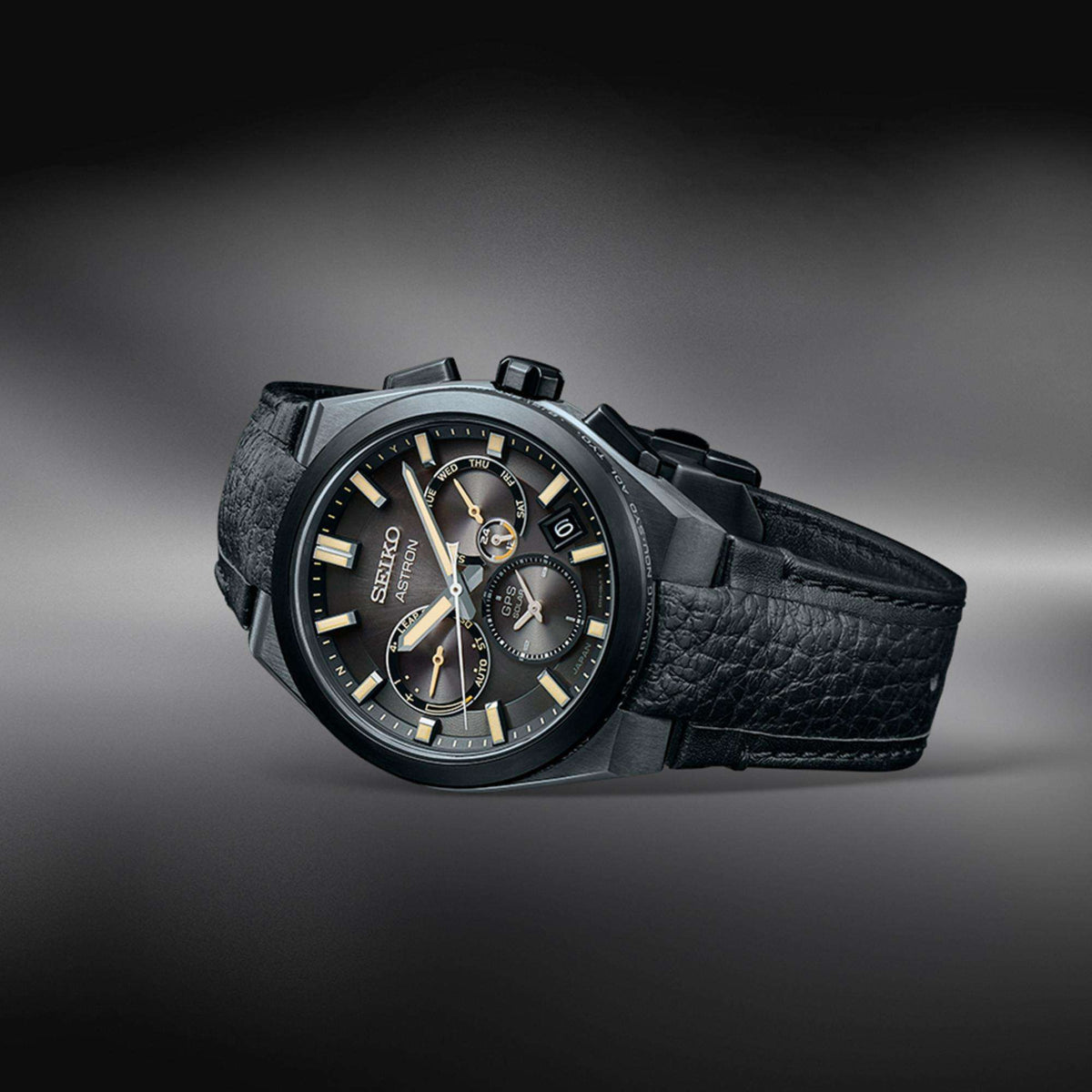 The watch laid flat on its side, emphasizing its sleek design and the arrangement of its black crown and pushers.