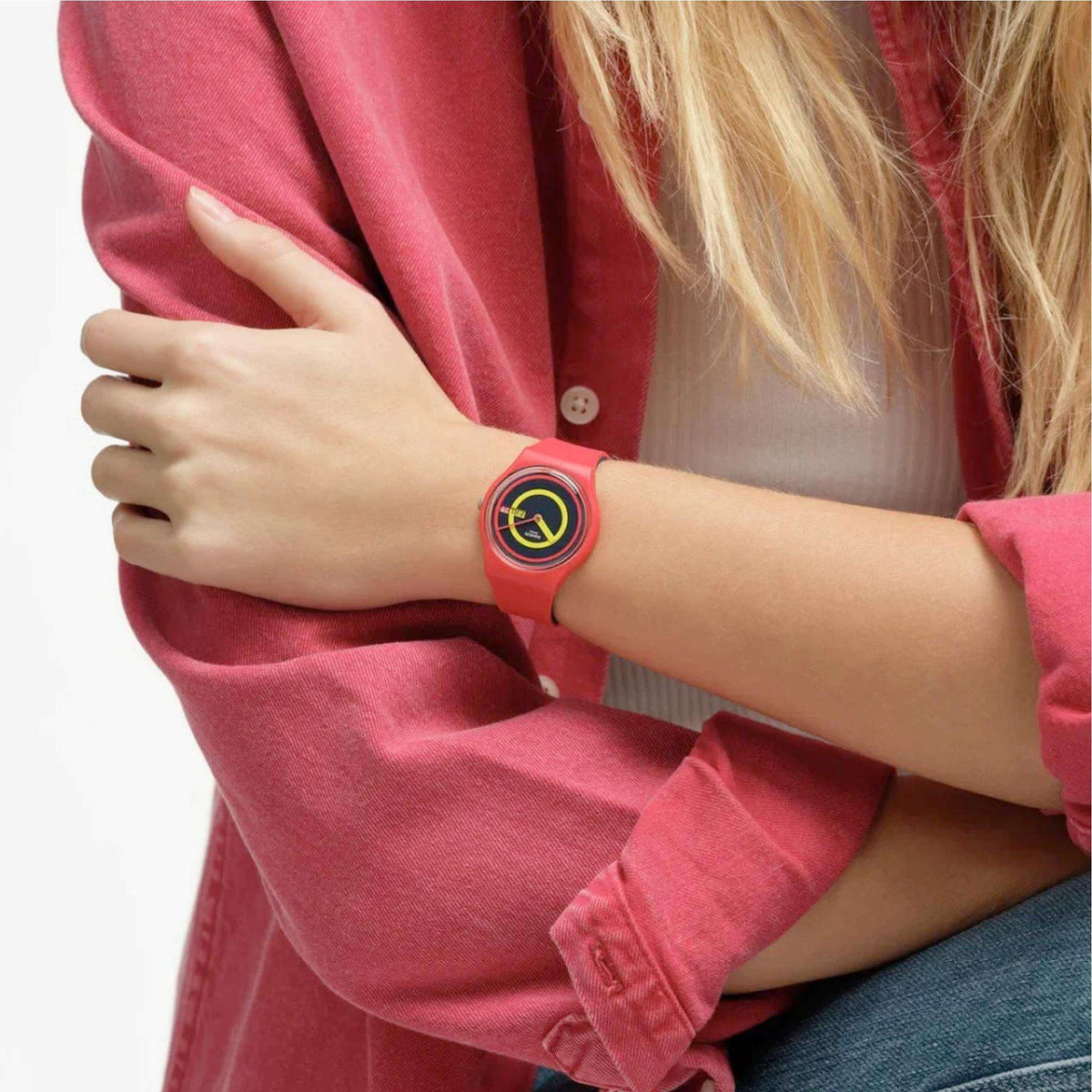 Pink silicone quartz watch on wrist with circular multicolor dial.