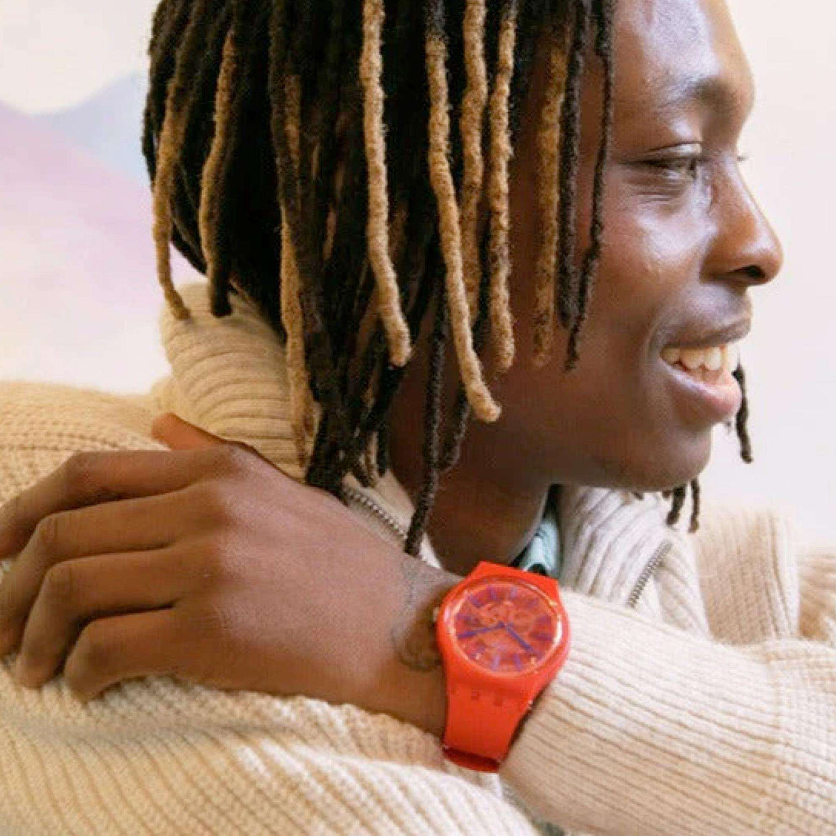 Red dial Swatch quartz watch on wrist, red silicone strap with knit sweater sleeve