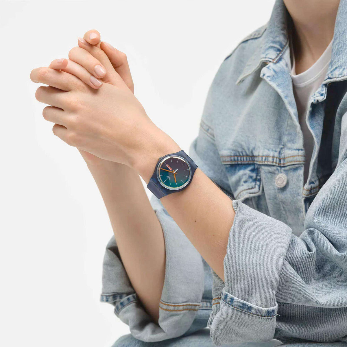 Teal dial quartz watch on wrist with blue silicone band and orange hands, round bezel.