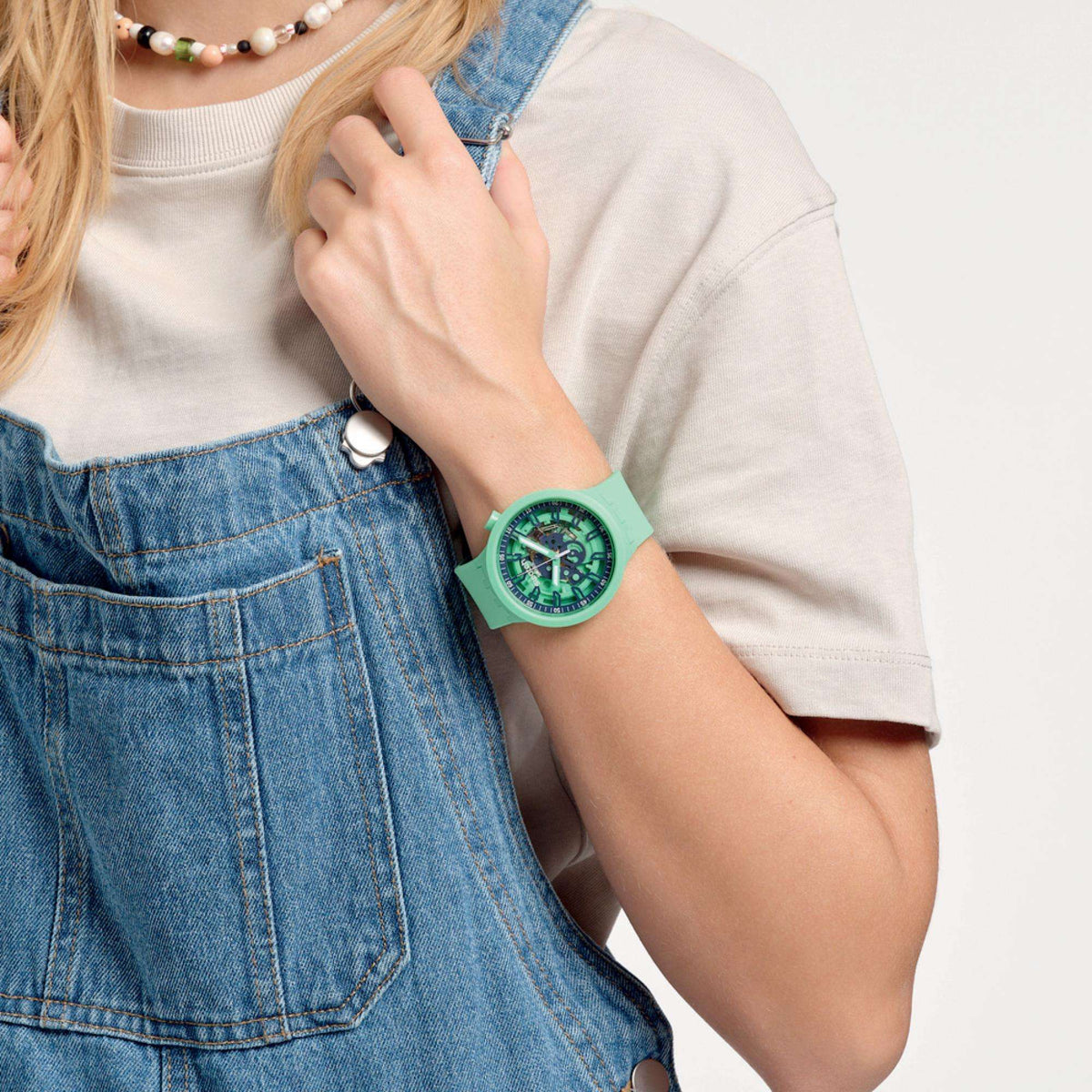 Swatch green quartz watch on wrist with silicone strap and green skeleton dial