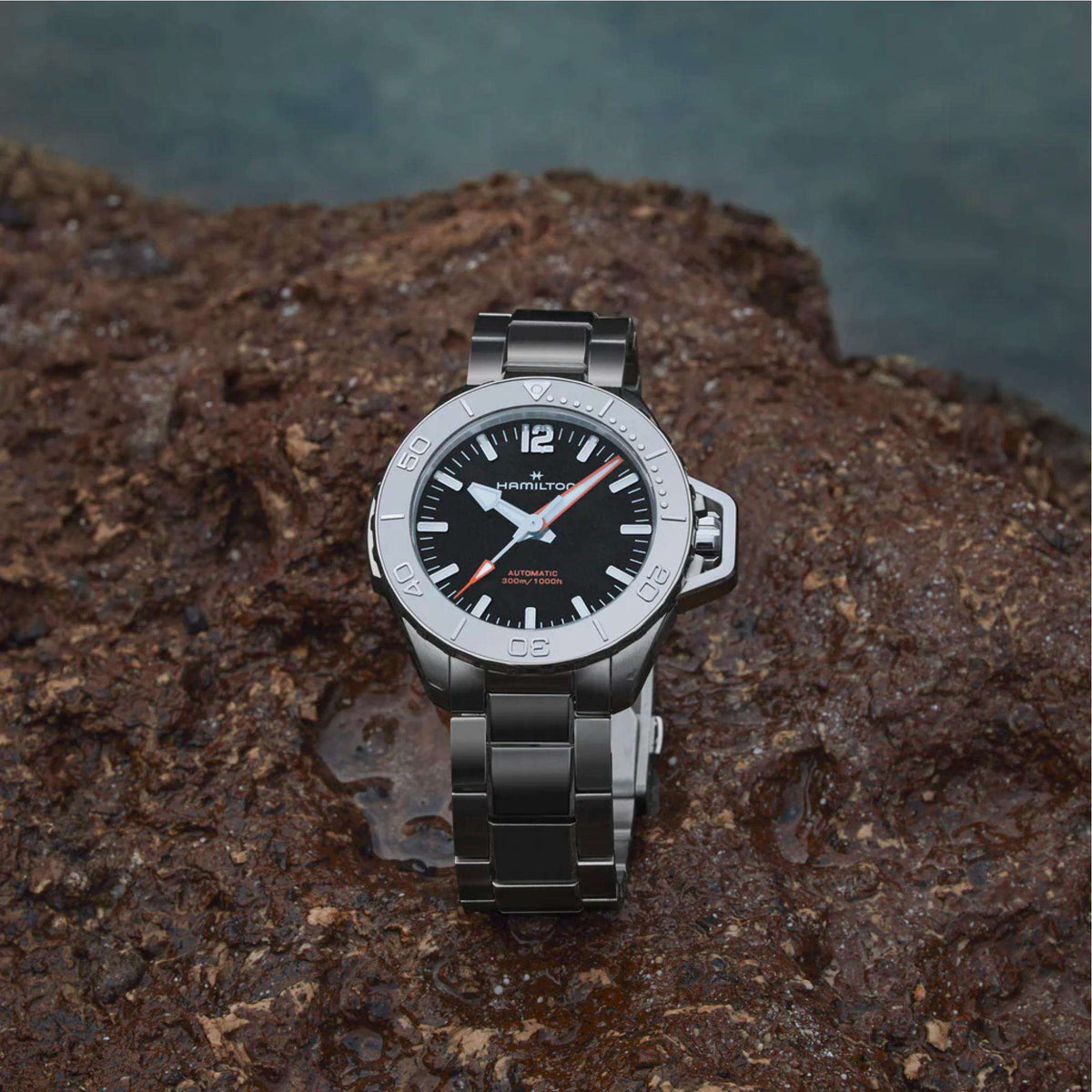 Men’s steel watch with black dial and orange accent markers on metal bracelet