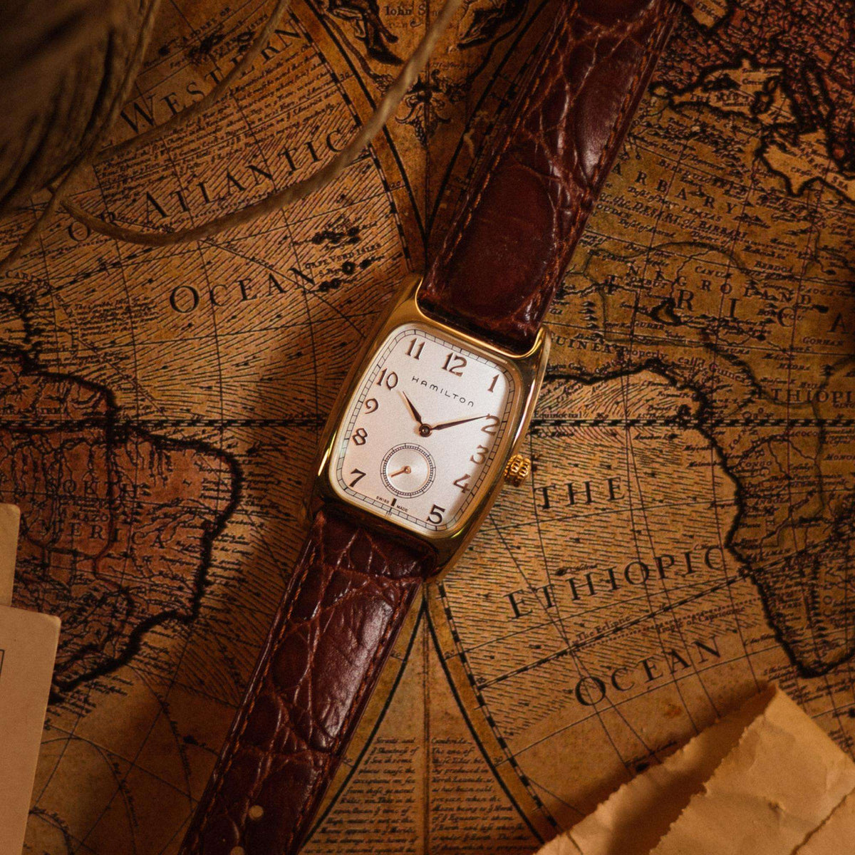 Hamilton American Classic Boulton H13431553 men's wristwatch set against a vintage map background displaying a white dial and a brown strap
