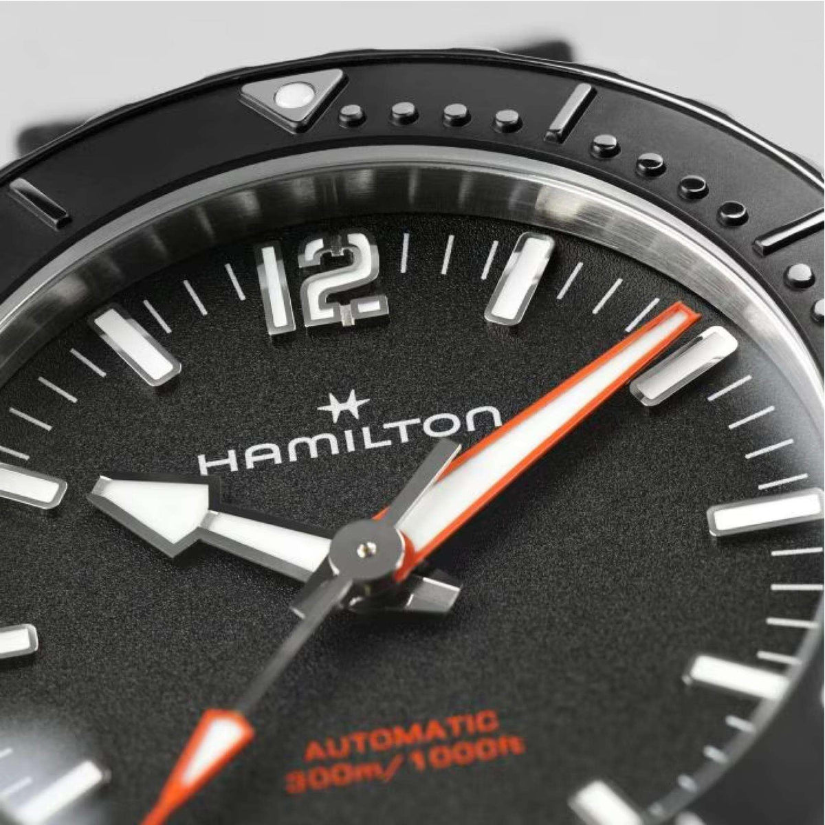 Hamilton automatic watch dial close-up with black face, baton markers, orange accents