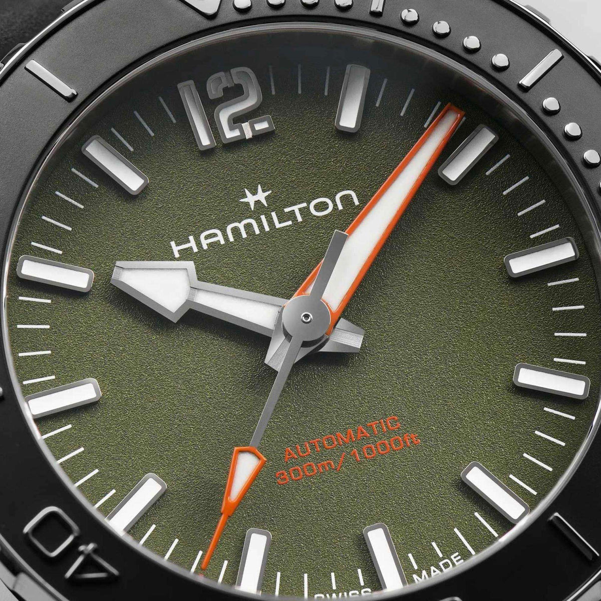 Green dial automatic 300m watch with orange accents, silver hands, and minute markers
