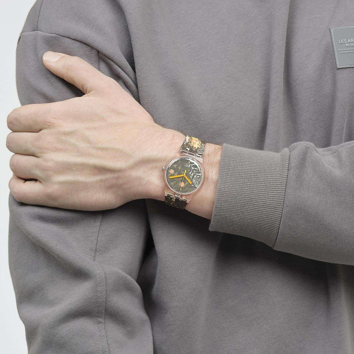 Quartz wristwatch with pink case, patterned brown-and-gold strap, orange hour markers