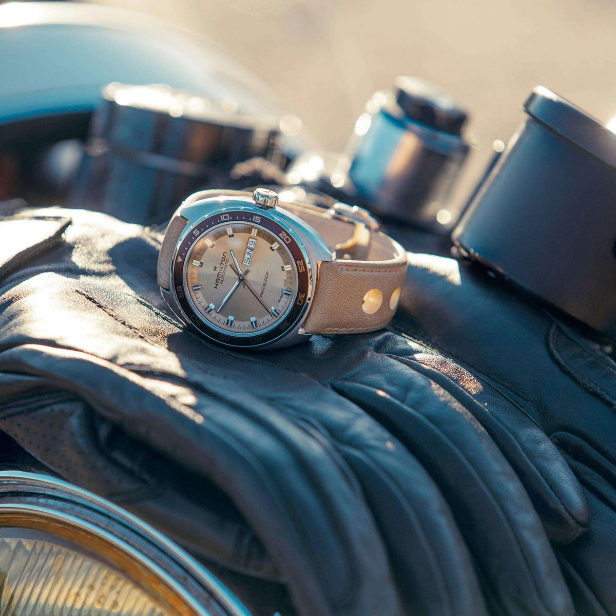 Men’s automatic watch resting on dark fabric, beige dial and tan leather strap