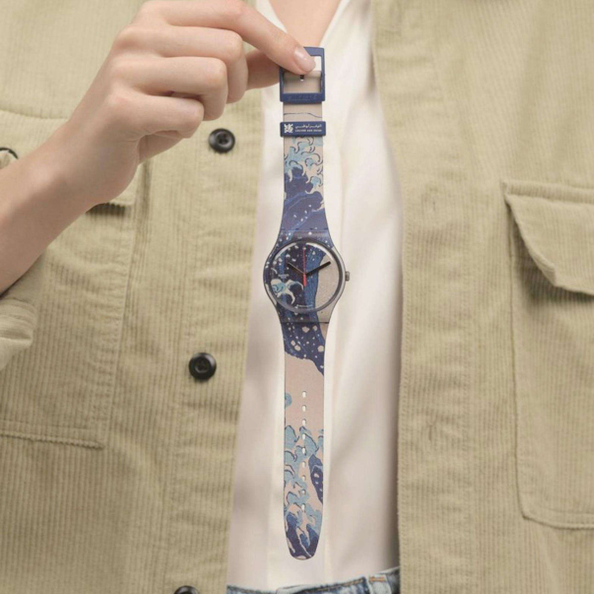 Wrist-worn quartz watch with blue patterned strap and round dark dial with red hands