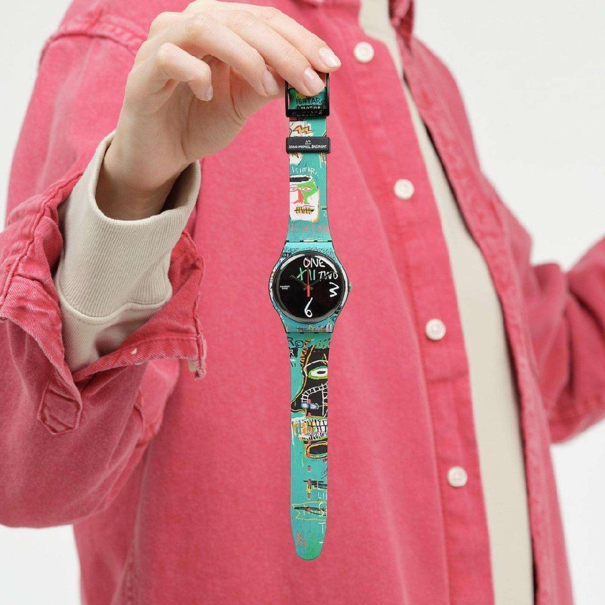 Quartz wristwatch with teal graphic strap and round black face, worn on wrist