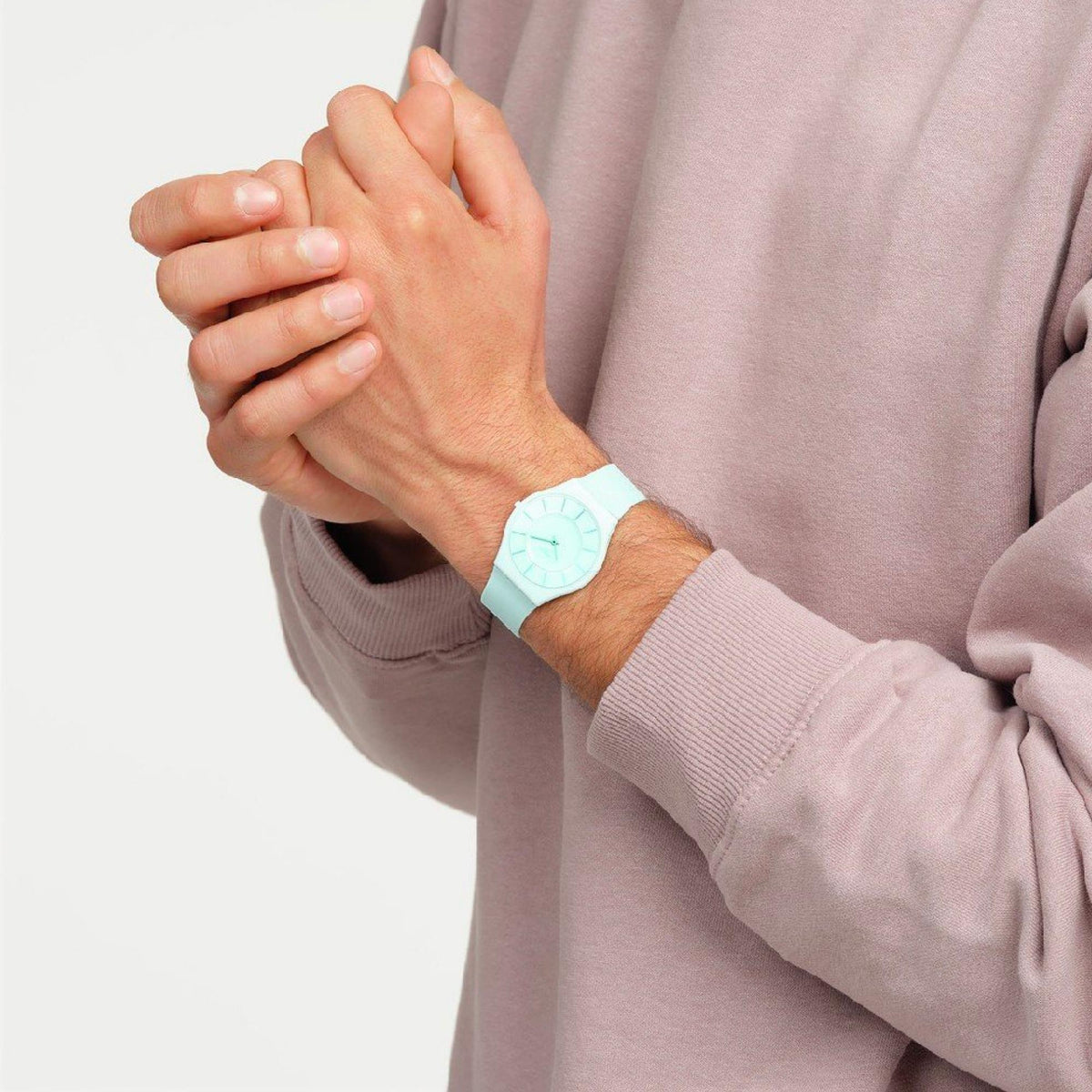 Turquoise wristwatch on a hand with light blue dial and silicone strap