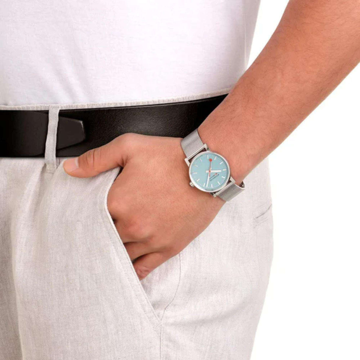 Mondaine Evo2 watch on wrist, turquoise dial with red hands, steel mesh bracelet