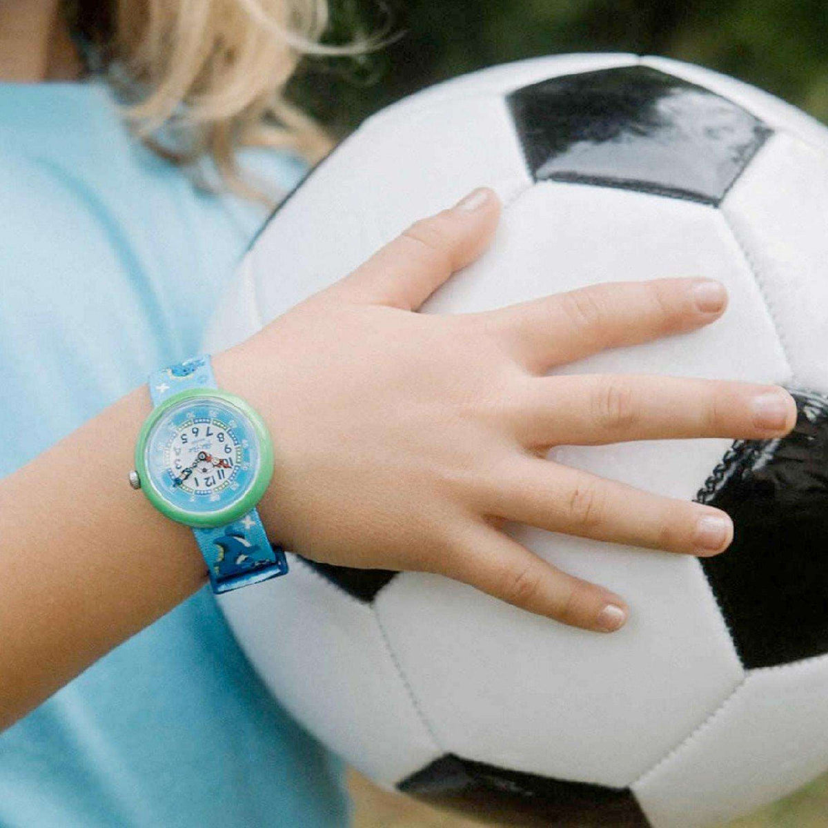 Flik Flak kids watch on wrist, blue strap and green bezel with soccer dial