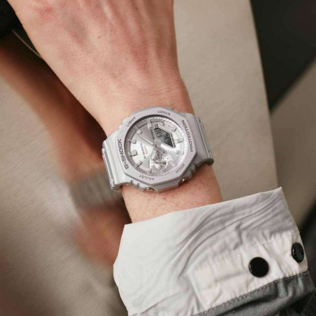 Silver G-Shock watch worn on wrist with gray dial and resin strap