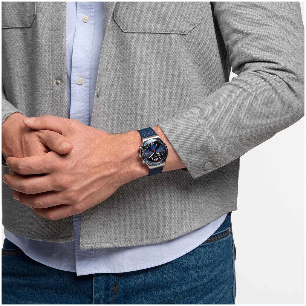 Blue chronograph watch worn on wrist with dark blue silicone band