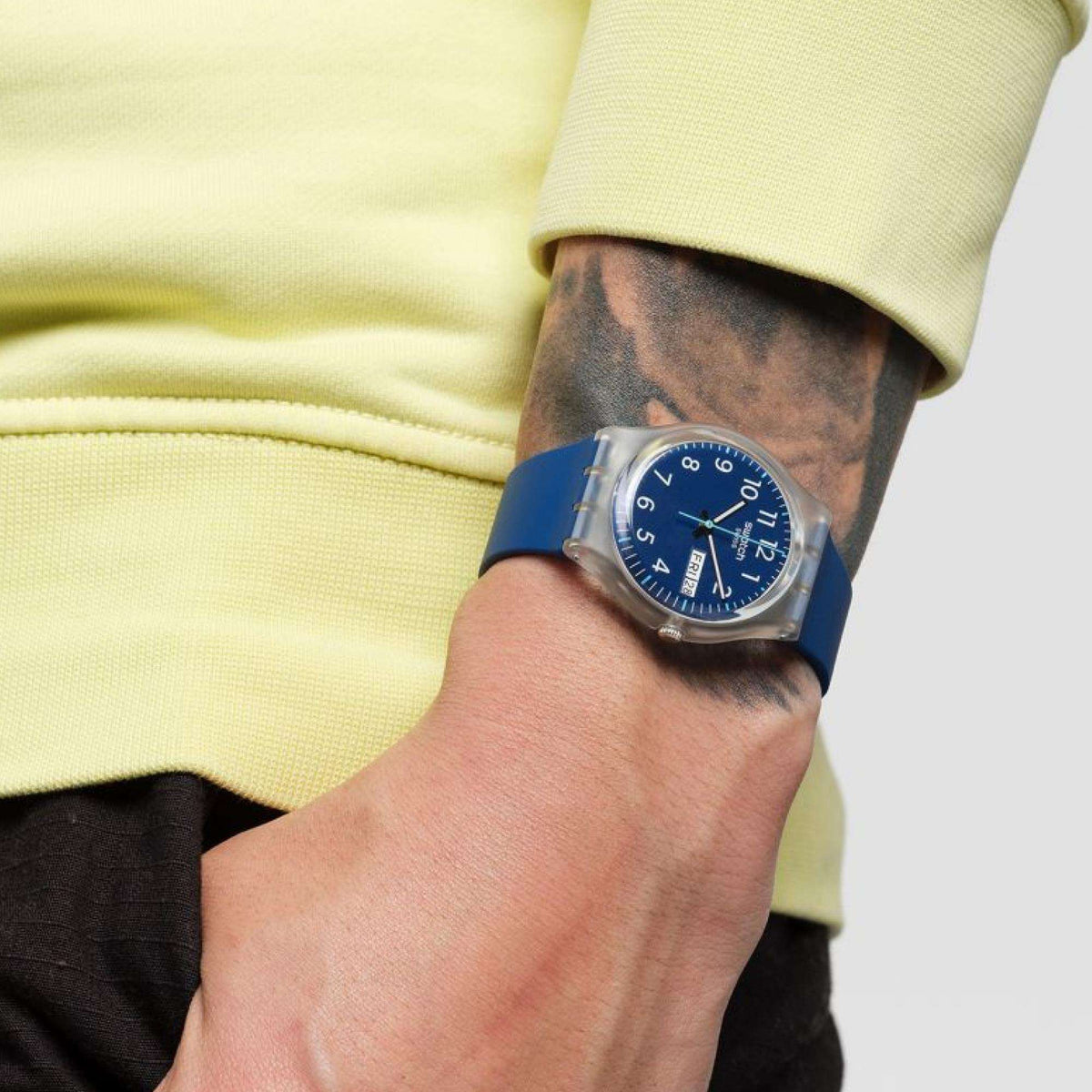 Navy blue dial watch on wrist with blue strap, worn under yellow long sleeve