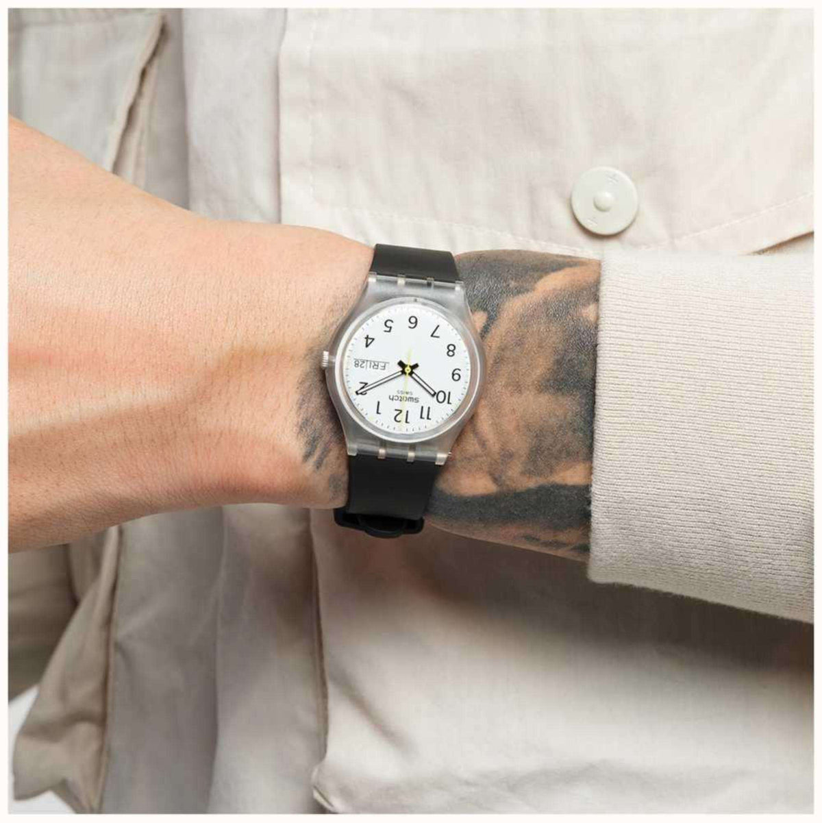 Black men’s wristwatch worn on a wrist with round white dial and date window