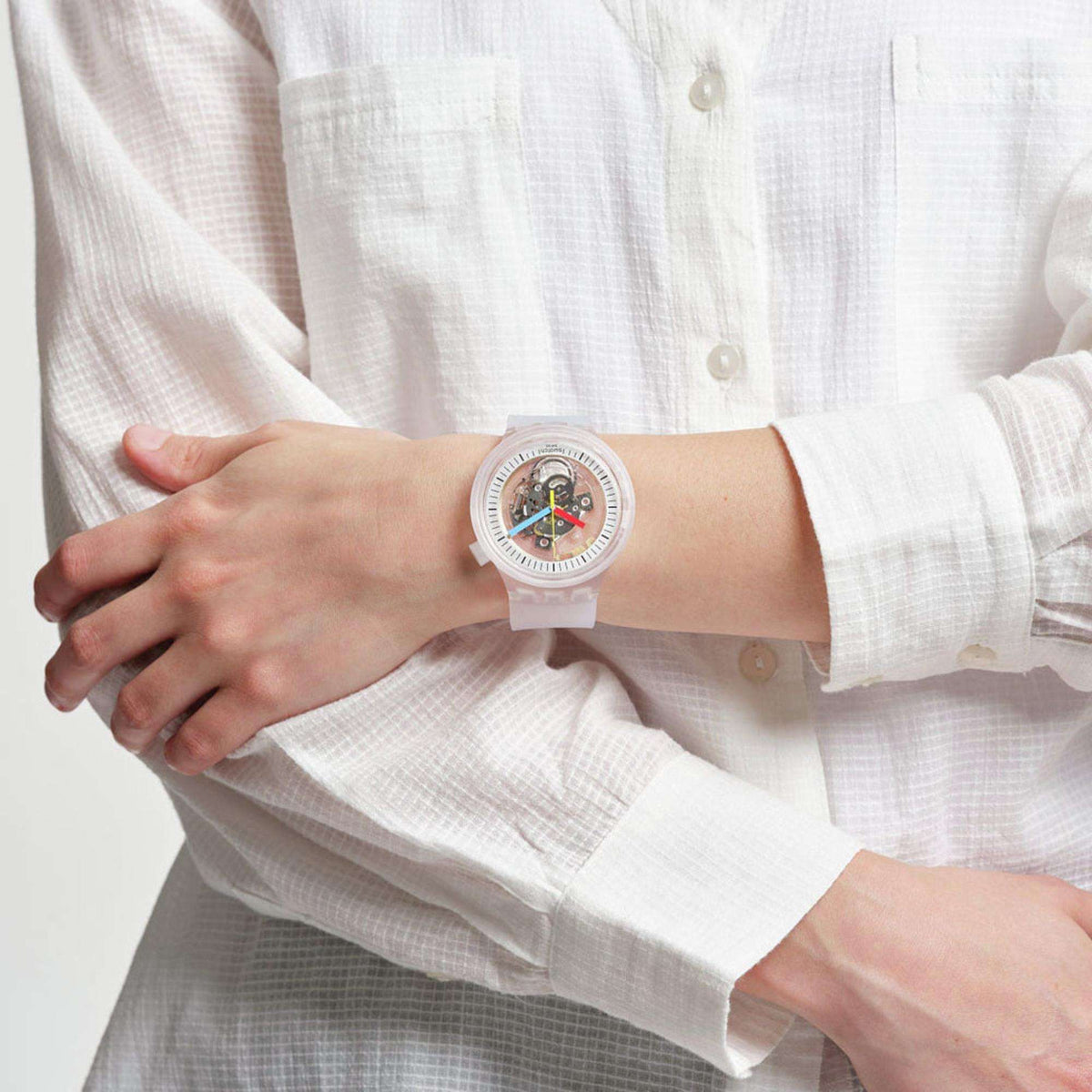 Swatch CLEARLY PAY! transparent watch worn on wrist with clear strap and exposed dial