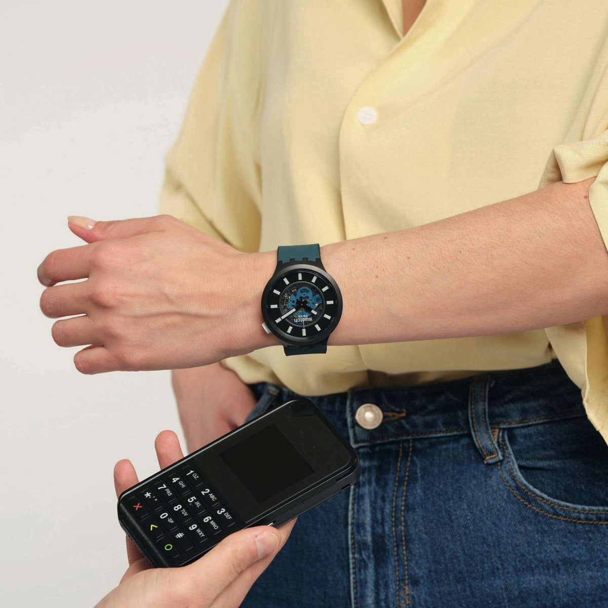 Analog watch worn with teal rubber strap; black dial with hour markers and subdials.