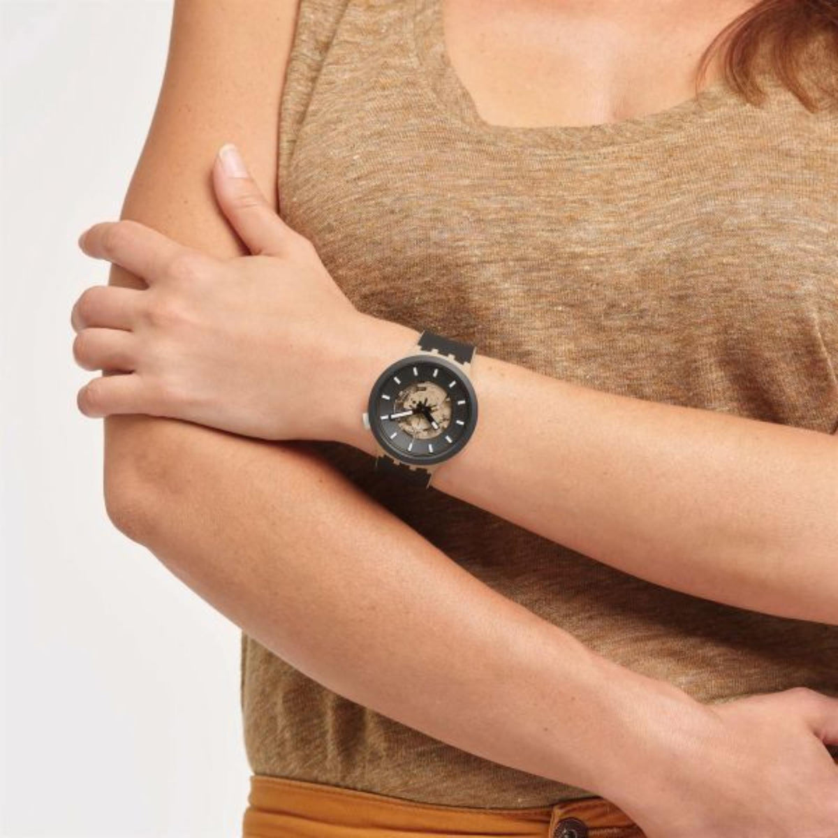 Silicone wristwatch on wrist, black dial with skeleton-style movement and white markers