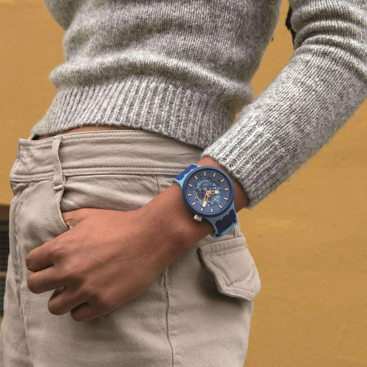Blue dial Swatch Big Bold watch on wrist with dark-blue strap and clasp over denim