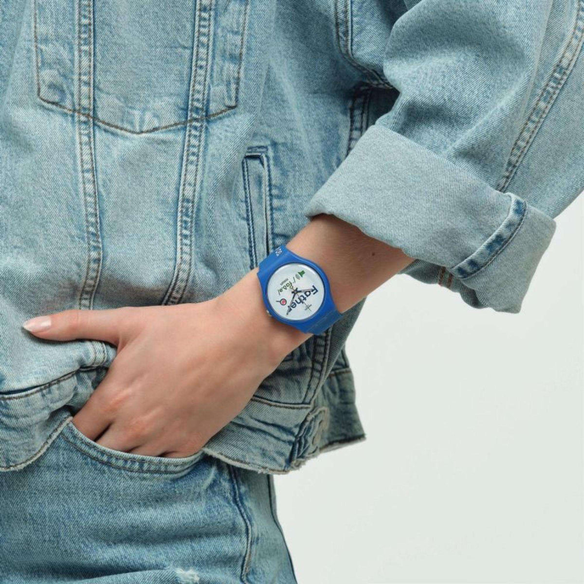 Blue silicone Swatch watch on wrist, white dial with Father graphic.