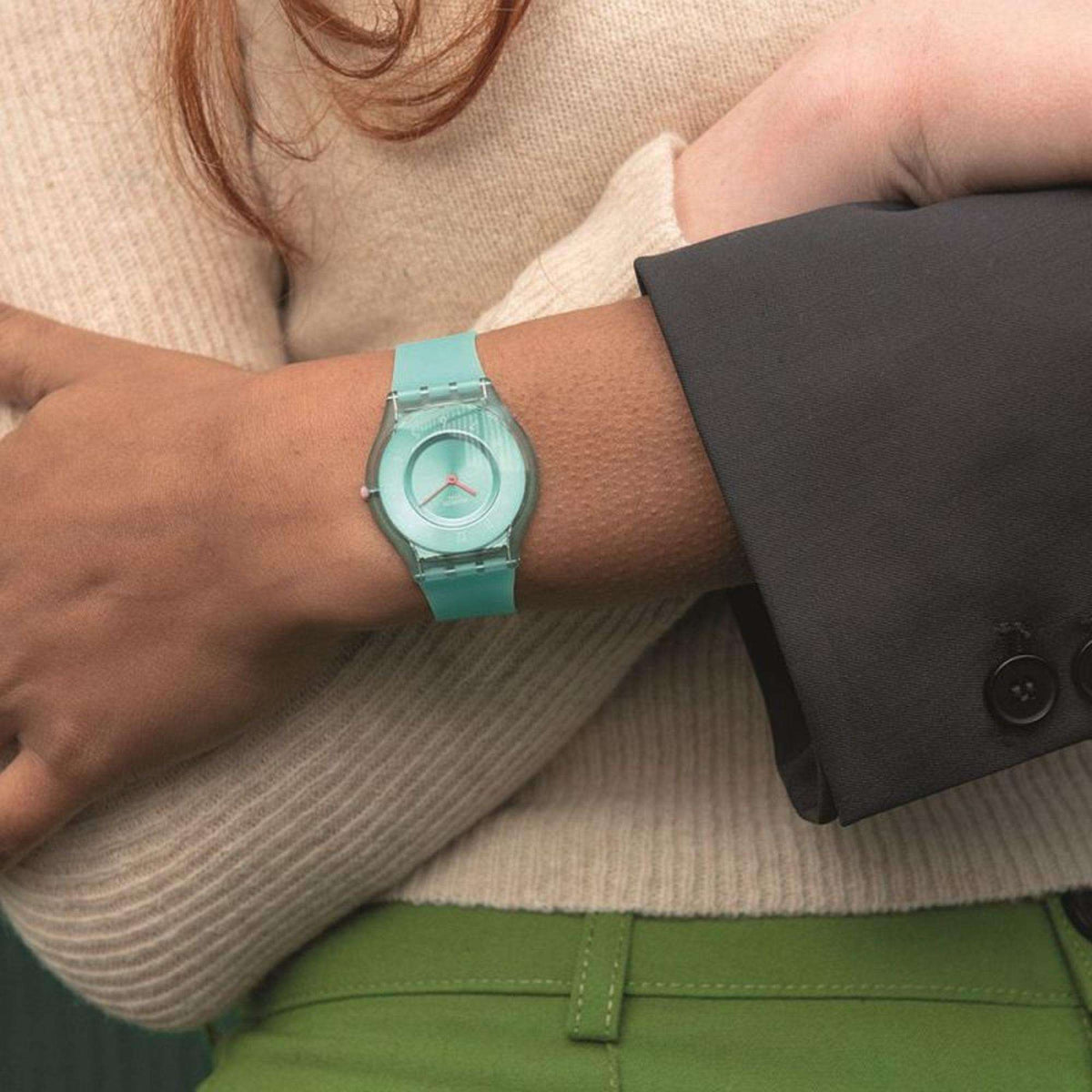 Swatch teal wristwatch on wrist with round dial and silicone strap