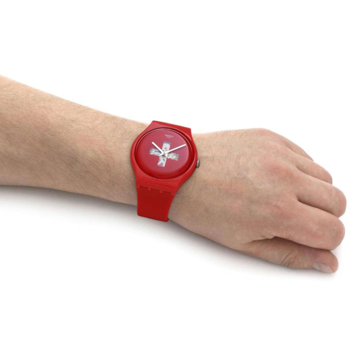 Red Swatch men's wristwatch on a hand, round dial with cross graphic, silicone strap.