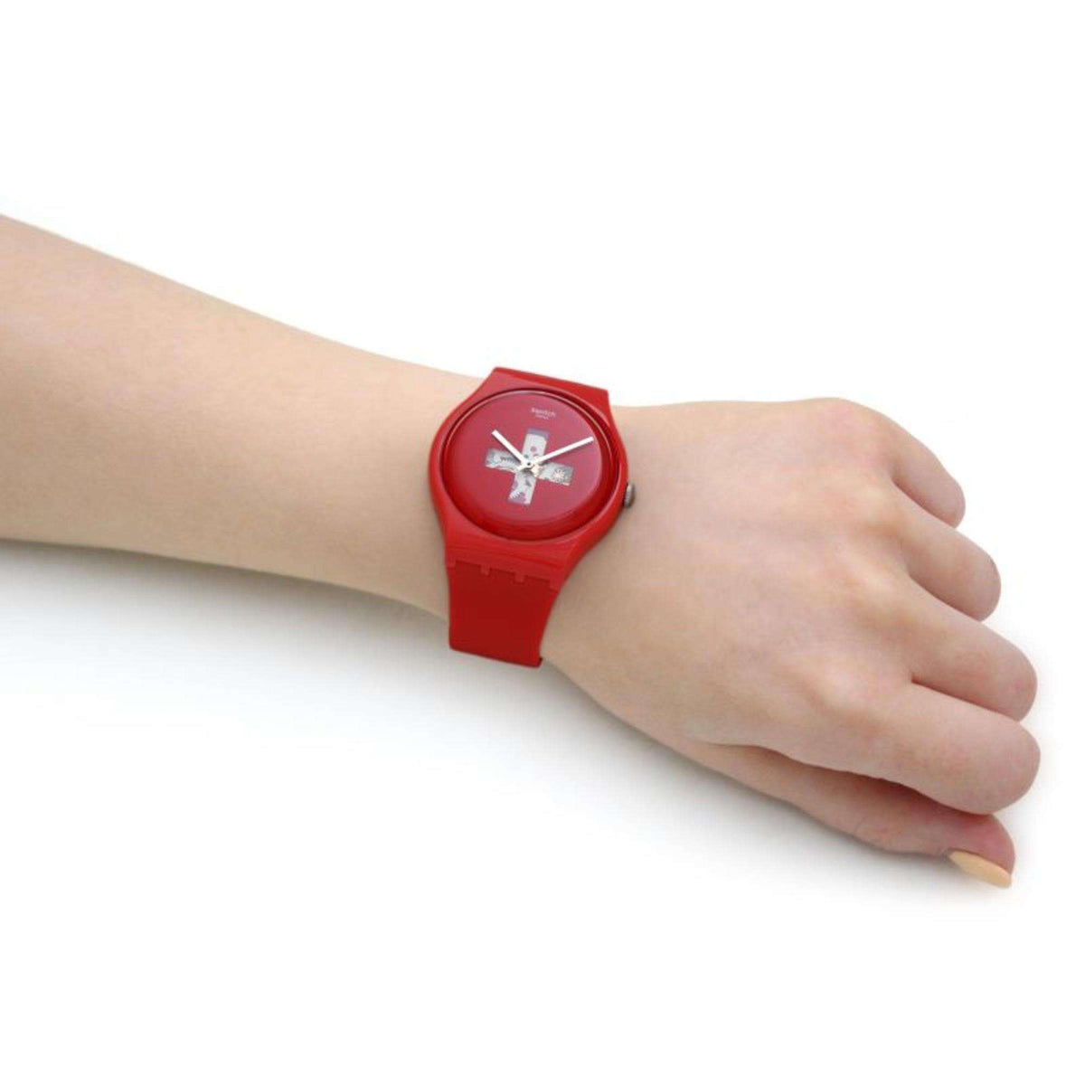 Red Swatch men's watch on wrist, round dial with cross graphic and red silicone strap.