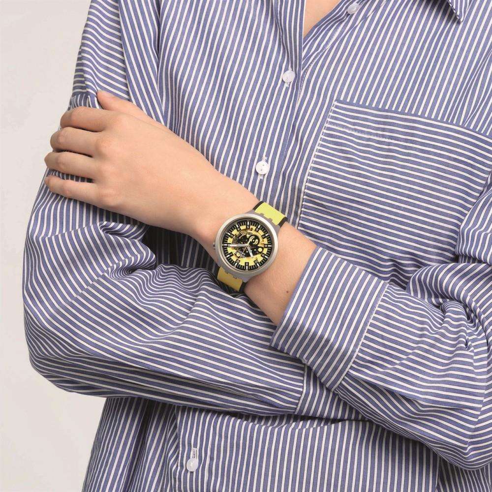 Men's Swatch wristwatch with yellow strap and black dial, gray case on forearm.