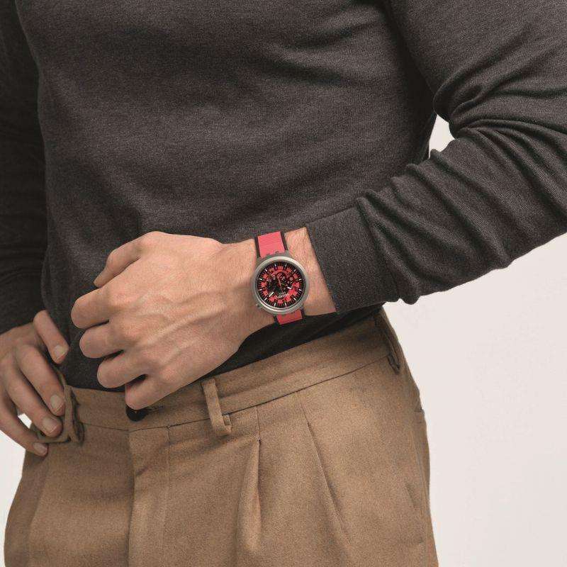 Red dial wristwatch with silver case and red rubber strap on arm