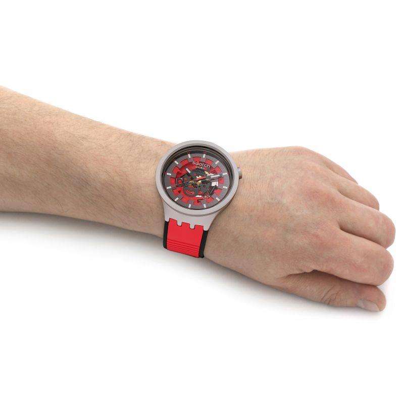 Red dial watch with silver bezel and red rubber strap on wrist