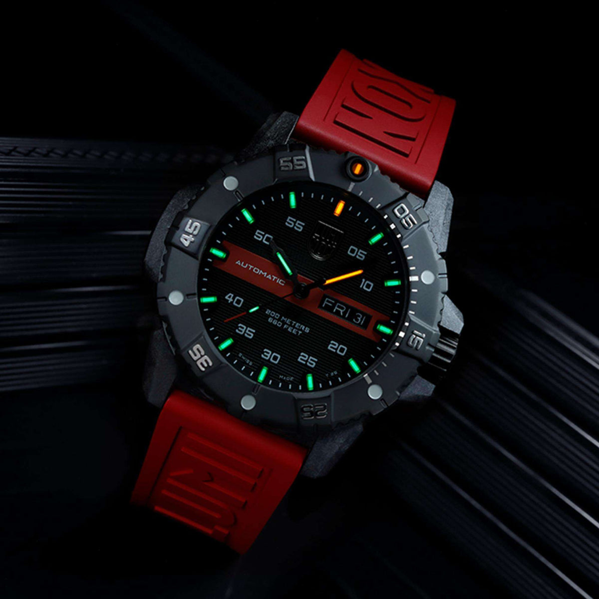 Automatic wristwatch with green lume accents on black dial and red silicone strap