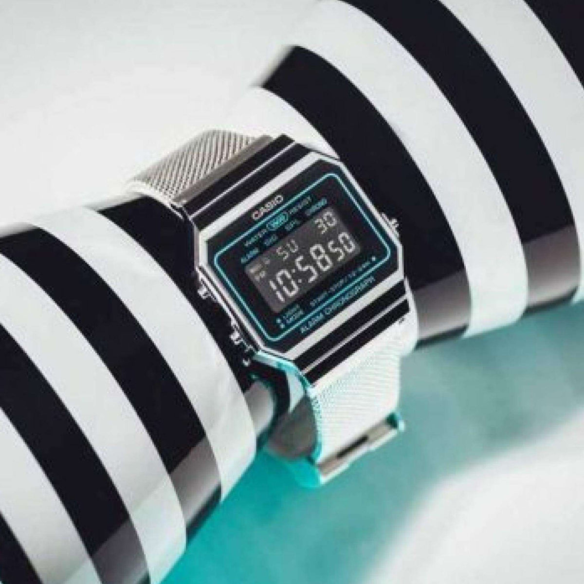 Casio vintage digital mens watch on striped cuff, blue backlit screen, silver mesh bracelet