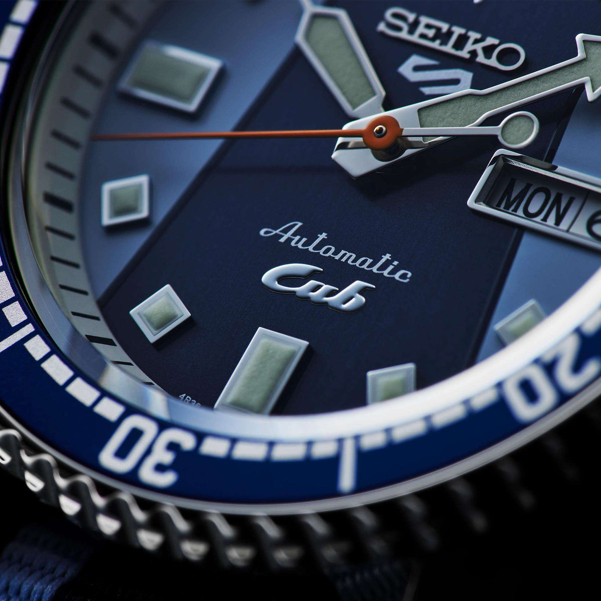 Close-up of blue watch dial with orange seconds hand and date window